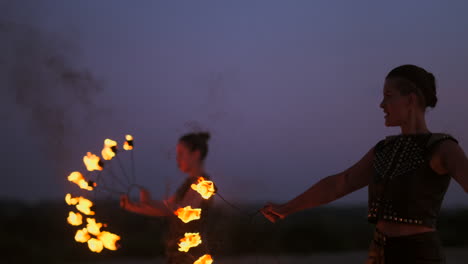 a group of professional circus performers with fire shows dance shows in slow motion using flame-throwers and rotating the torches burning objects