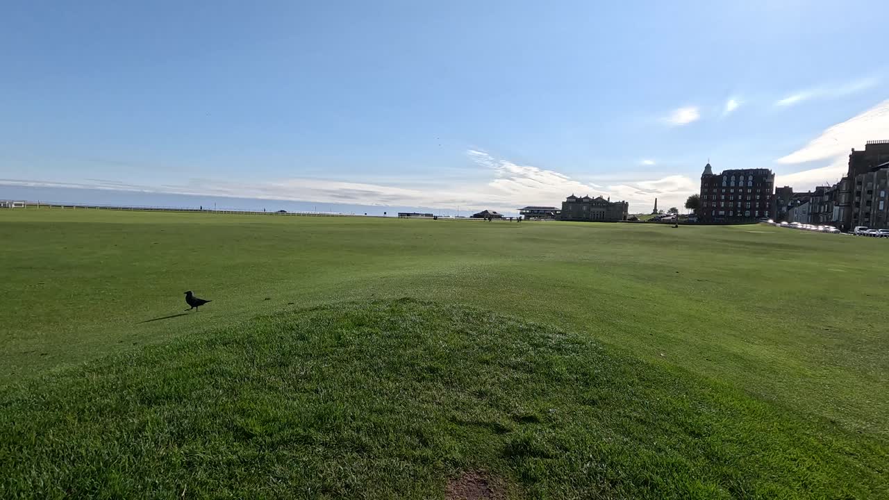Camera moves over old stone bridge on green golf course, bright daylight, wide scenic view