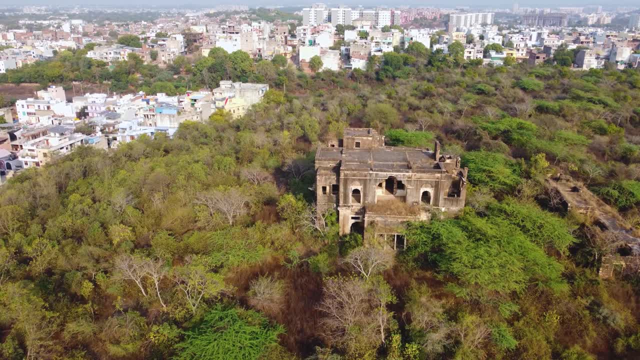 Drone shot of an abandoned ruins haunted building covered with forest in india