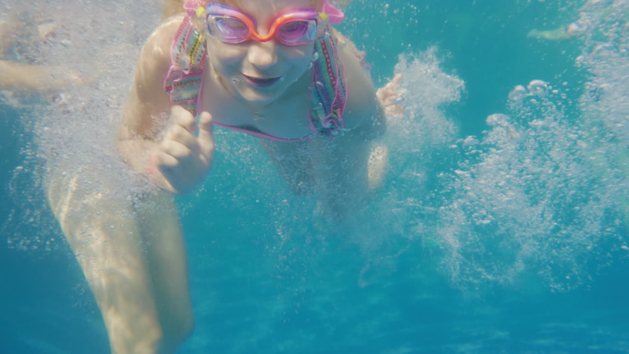 6세 소녀가 수영장에서 수영하는 법을 배웁니다. 어머니가 수중 슬로우 모션 비디오를 도와줍니다.