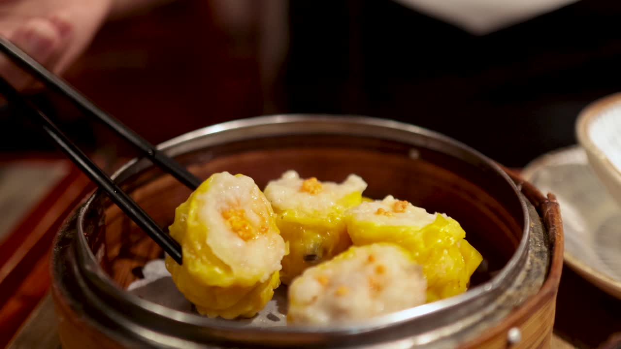 palillos para comer recogiendo siu mai de un vapor de bambú