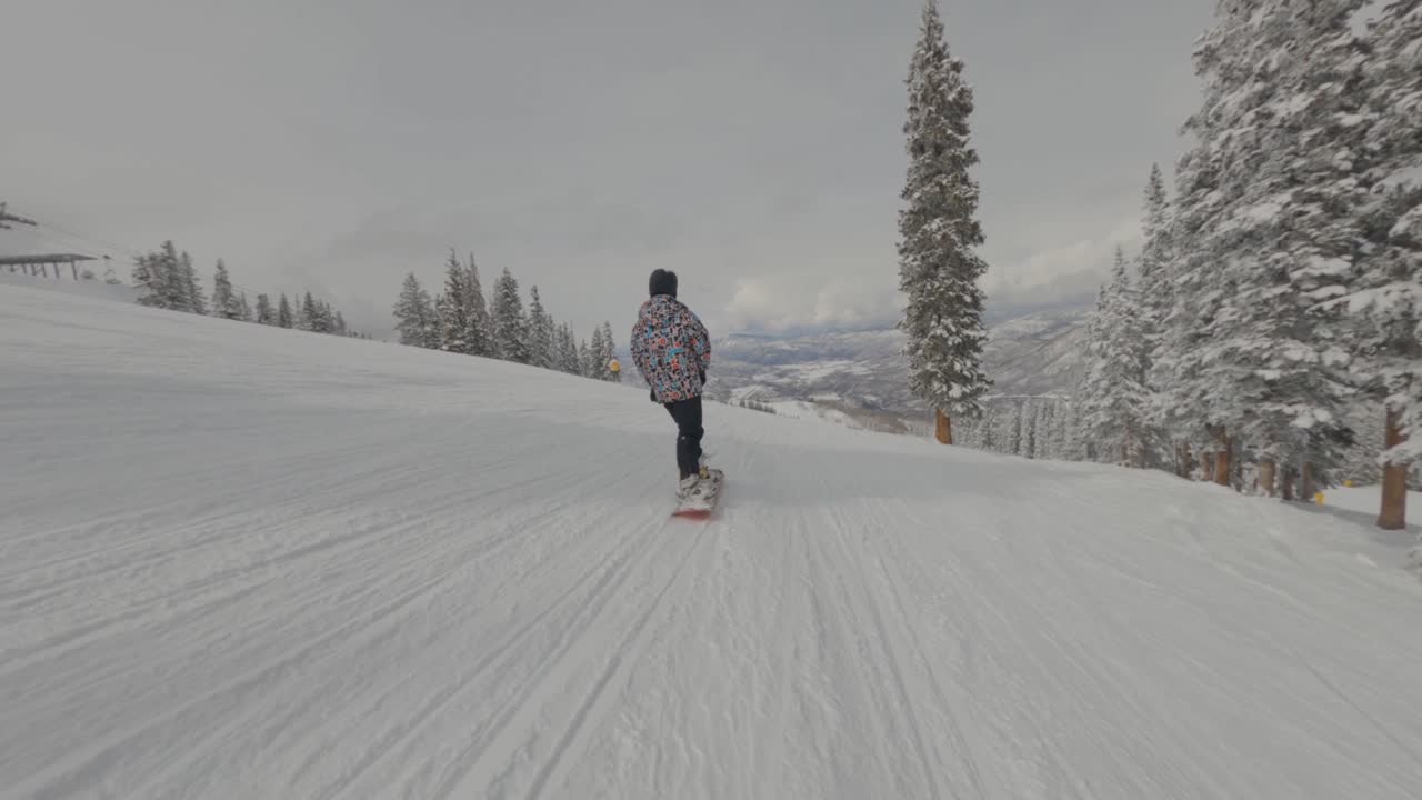 one man snowboarding down white slopes, Aspen, Colorado. Winter sports concept . Tracking and follow shot