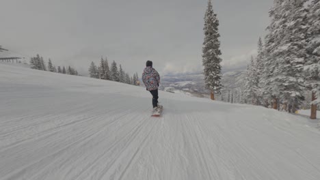 one man snowboarding down white slopes, aspen, colorado. winter sports concept . tracking and follow shot