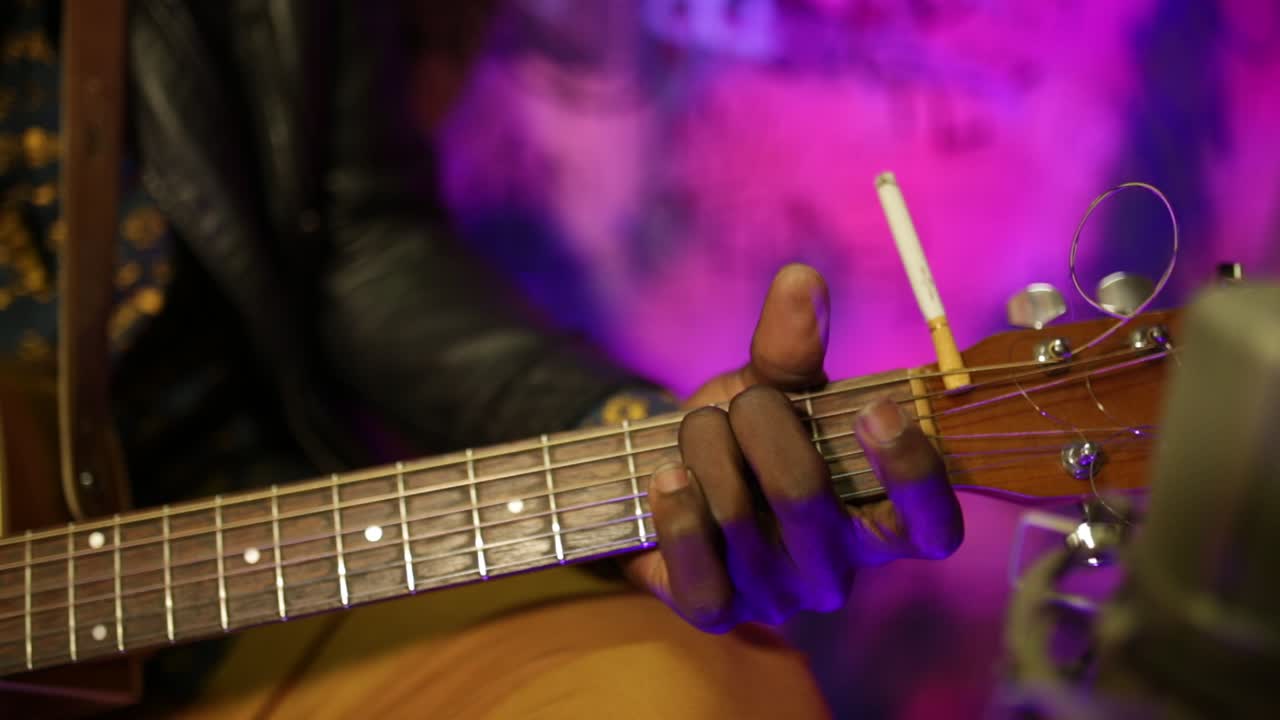 Persona che suona la chitarra con una sigaretta sulla testa