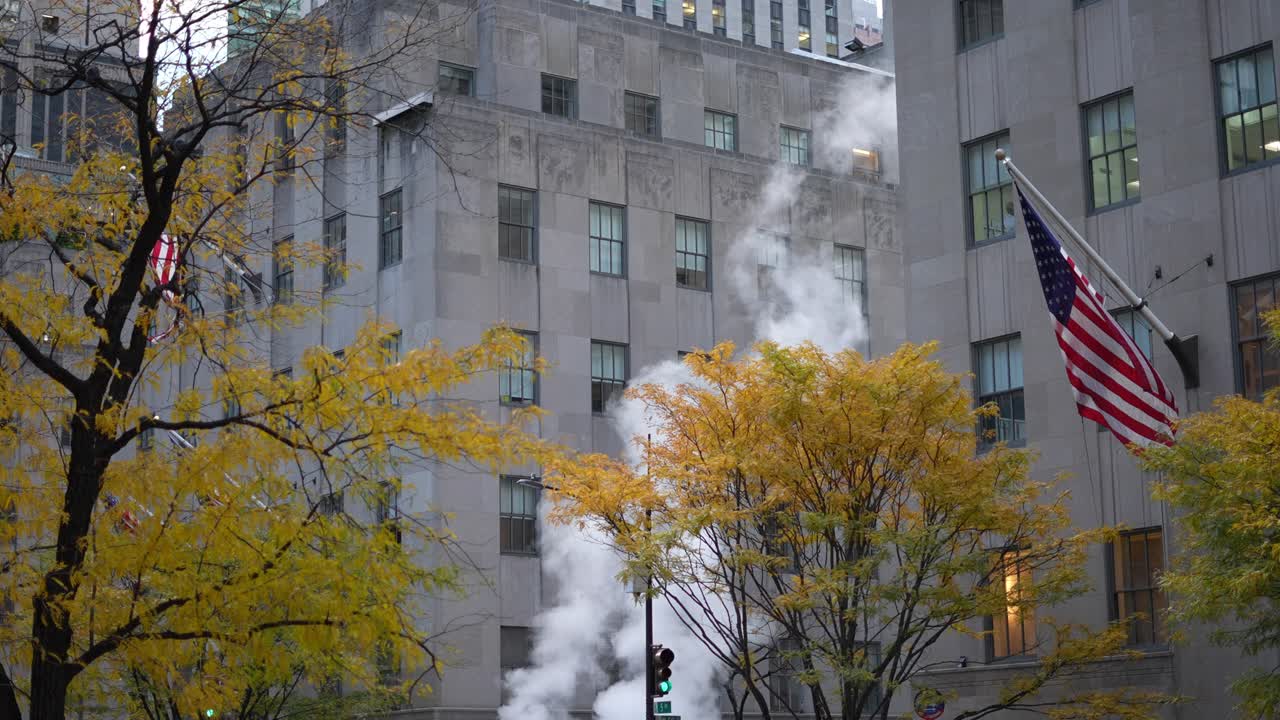 Busy Manhattan street with city bus, autumn foliage, and steam rising from street vents near high-rise buildings