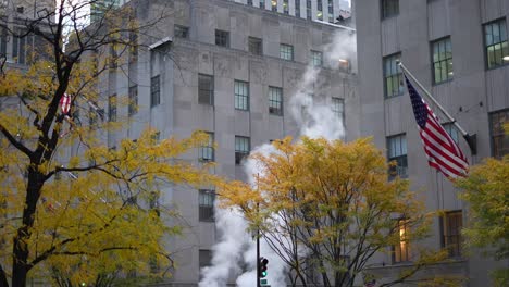 busy manhattan street with city bus, autumn foliage, and steam rising from street vents near high-rise buildings