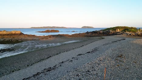 guernsey north east coast low flight over beach to little russell channel across to herm and jethou over rocky shoreline in late summer sun on calm day with clear sky