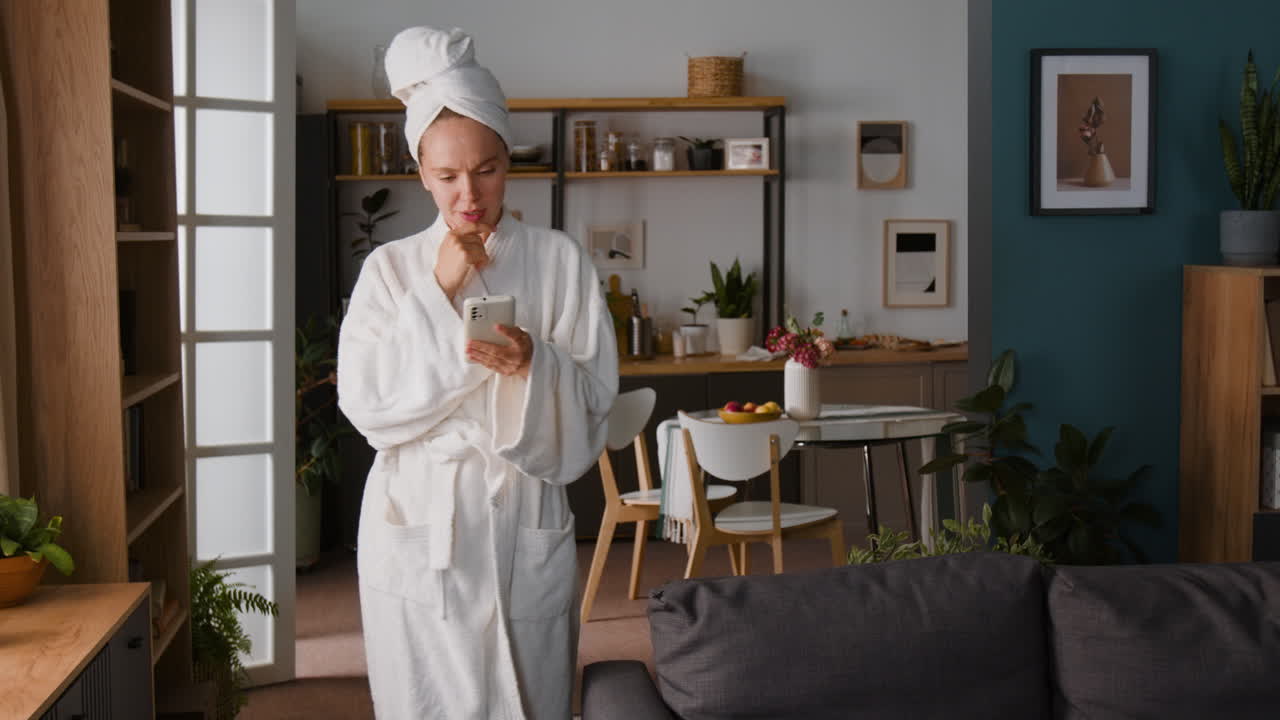 Woman in Bathrobe Using Smartphone at Home