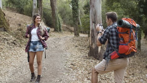 male hiker with camera taking pictures of his happy girlfriend