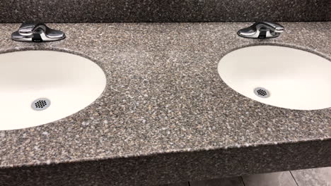 bathroom granite countertop with two oval white under mount sinks with faucet and tiled walls and floors around