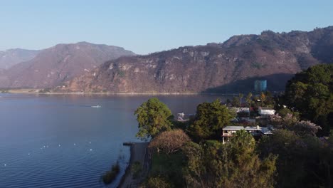 aerial rises over blooming tree to reveal lake atitlan bay, guatemala