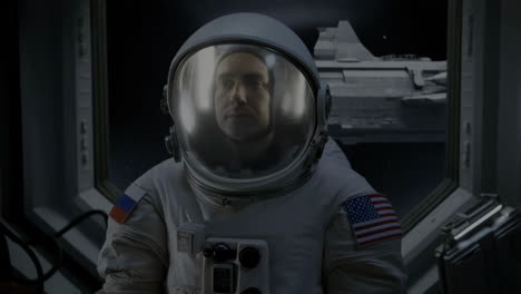 astronaut in space suit looking out a window in a spacecraft