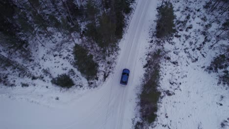 winter road top view over blue car in the forest