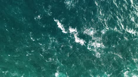 aerial top down static overview of white peak waves building and crashing on green water, bird's eye view