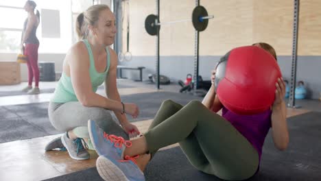 mujer diversa inalterada mujer motivadora mujer decidida entrenando con pelota de medicina en el gimnasio, cámara lenta