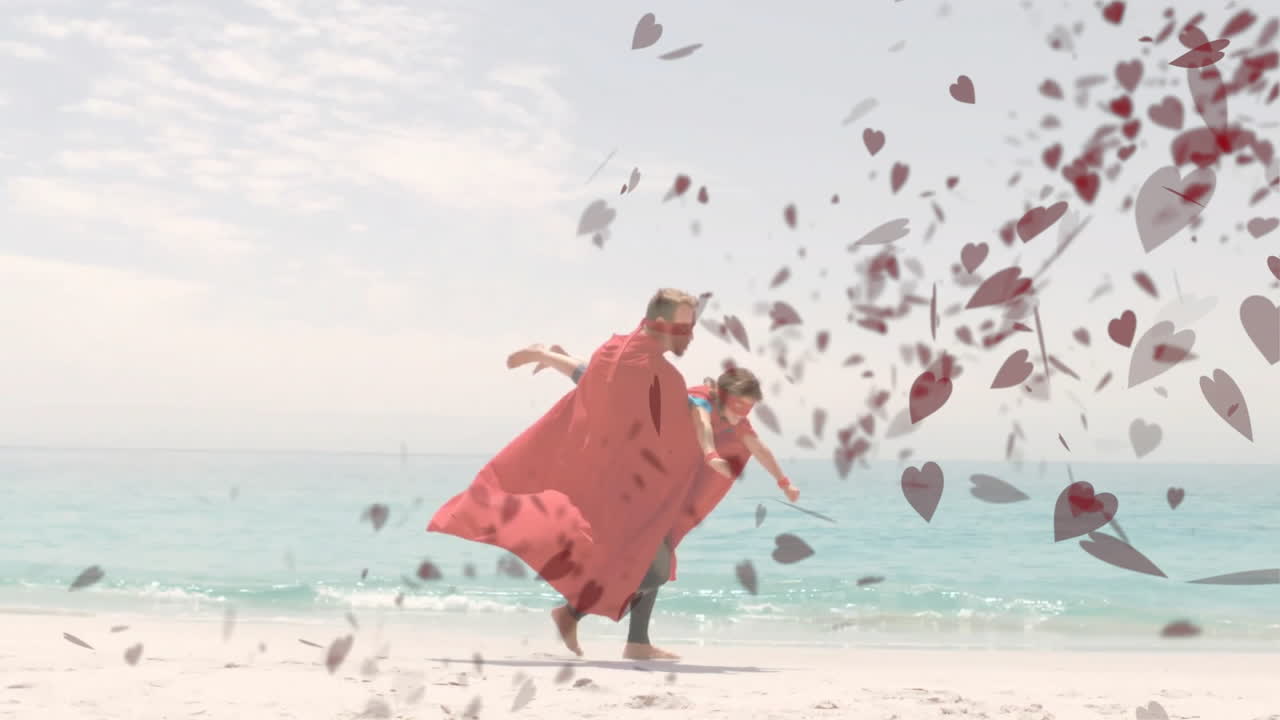 Father and child wearing capes running on beach with heart animation overlay