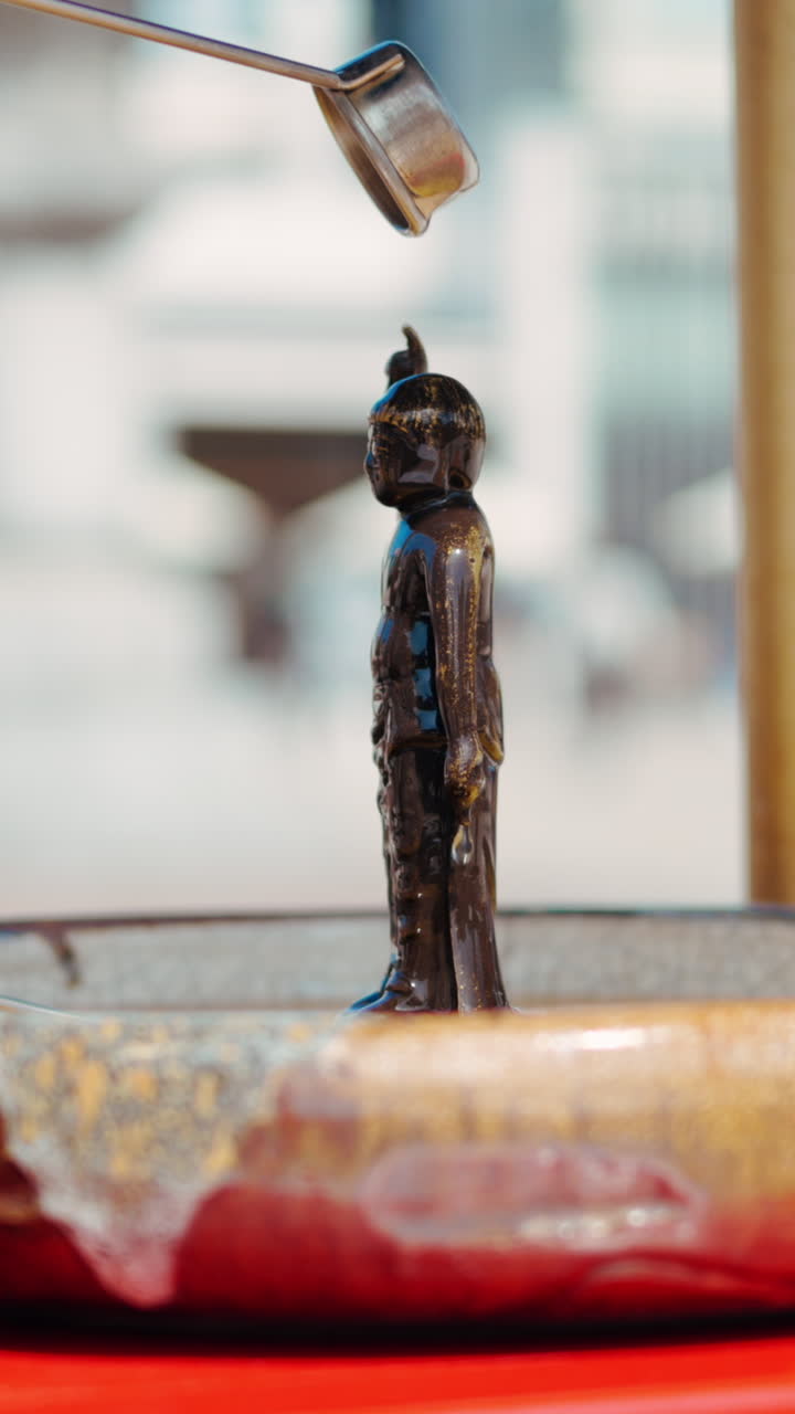 Close up of a purification water fountain at the Tsukiji Hongan-ji Temple with people walking on the blurred background. Vertical