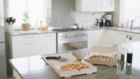 pizza cutter and two takeaway pizzas in boxes on kitchen counter