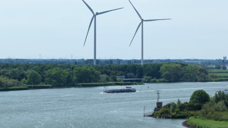 wind turbines spin by river with passing cargo ship, tranquil scene in barendrecht