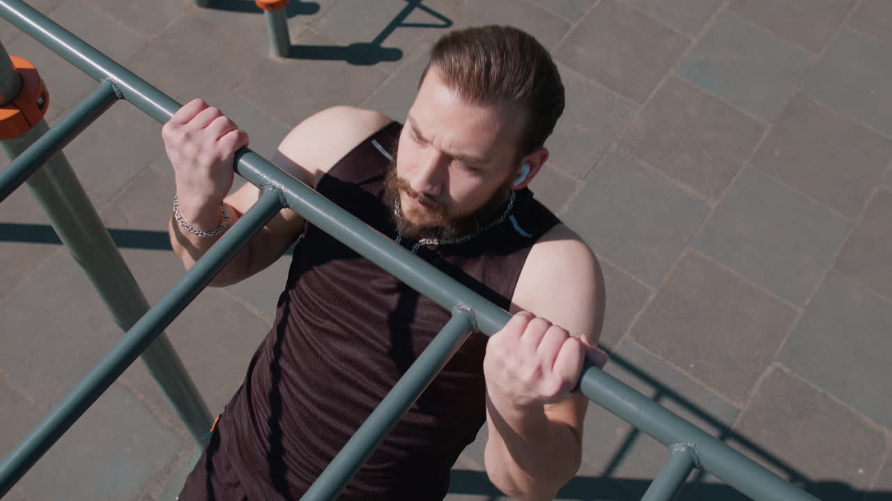 Athletic lebanese man in sportswear doing pull ups exercises on horizontal bar pumping up back