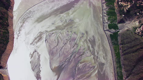 aerial zooming in close up of river with its shiny water by harsh sunlight, surrounded by mountains, forest and houses