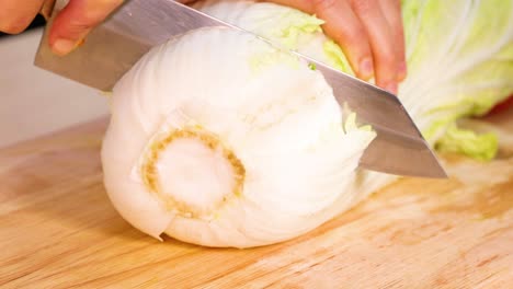 slicing cabbage with a knife on wooden board