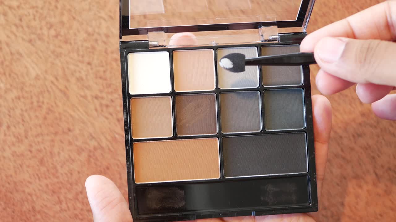 브러쉬 를 사용 하여 눈 그림자 를 쓰는 여자