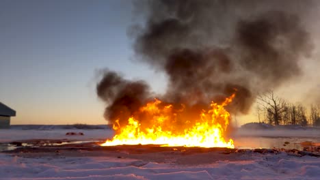 huge flames from burning oil spill send thick dark black smoke billowing into the sky