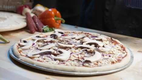 Hands-of-a-skilled-chef-orginize-and-setting-up-fresh-mushrooms-cut-on-pizza-dough-with-mozzarella-cheese-and-juicy-red-sauce