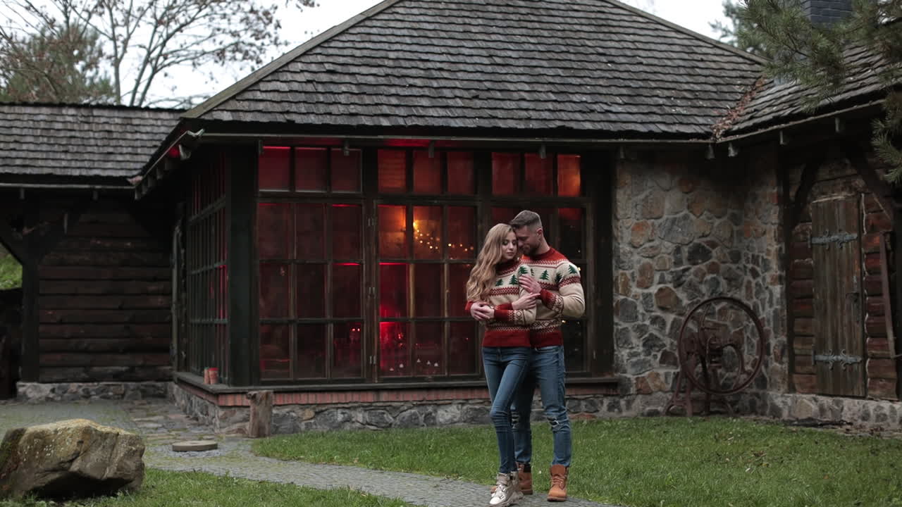 Happy couple enjoying each other's company near the country house. Beautiful pair hugging outside the nice wooden manor.