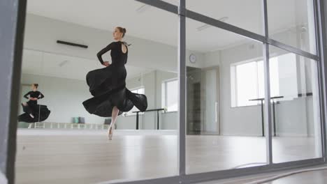 caucasian female ballet dancer practicing ballet during a dance class in a bright studio