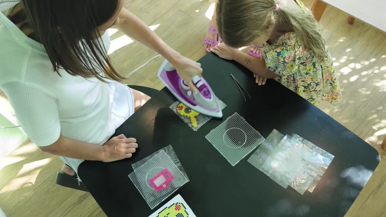 madre e hija creando arte de píxeles con un hierro