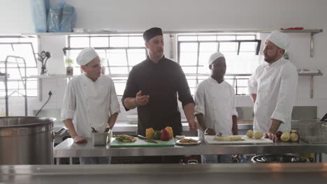 chef masculino diverso instruyendo a un grupo de cocineros masculinos aprendices en la cocina, cámara lenta