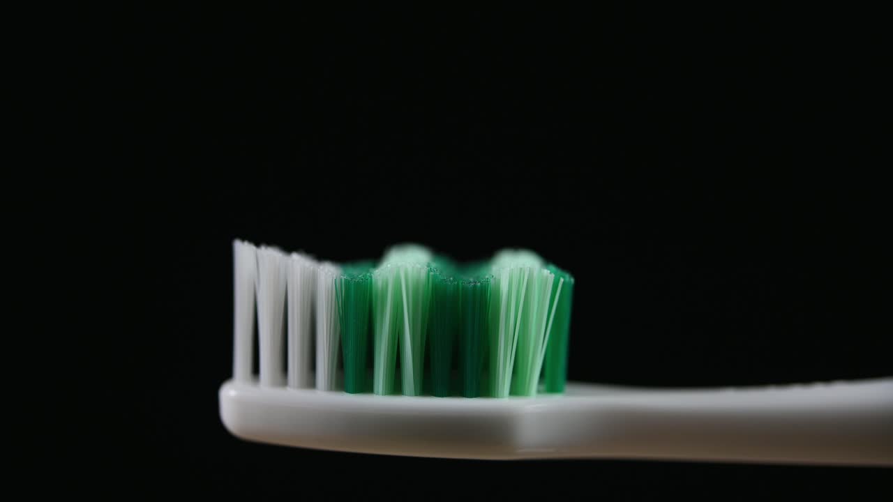 un cepillo de dientes se alejó con un fondo oscuro que revela las cerdas y el mango