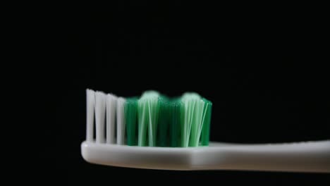 a toothbrush zoomed out with a dark background revealing bristles and the handle