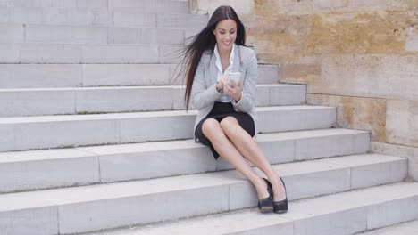 Glücklicher-Manager-Mit-Telefon-Und-Auf-Der-Treppe-Sitzend