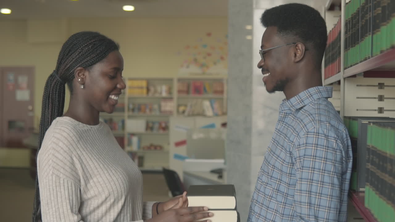 mujer negra le da algunos libros a un niño negro en la biblioteca