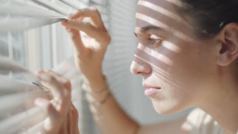 woman opening blinds and looking through window