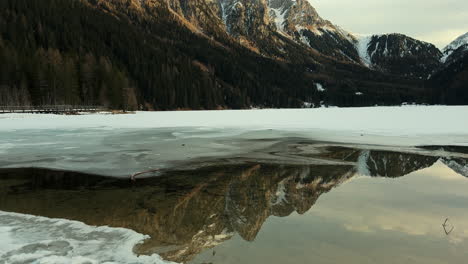frozen alpine lake with mountain reflections
