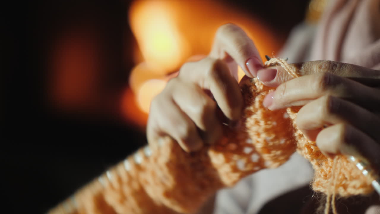 크리스마스 전 벽난로 옆에서 저녁 - 한 여성이 따뜻한 옷을 짜다 4k 비디오