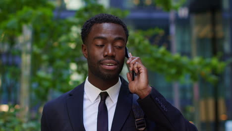 Close-Up-Of-Young-Businessman-Wearing-Suit-Talking-On-Mobile-Phone-Standing-Outside-Offices-In-The-Financial-District-Of-The-City-Of-London-UK-2