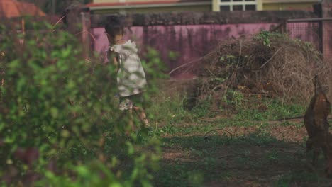 Toma-Estática-De-Mano-Detrás-De-Un-Arbusto-De-Una-Niña-Con-Flores-En-La-Mano-Mientras-Recoge-Más-Plantas-En-El-Jardín