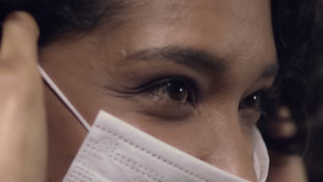 Attractive-Latina-or-black,-mixed-race-woman-putting-on-a-face-mask---isolated-close-up