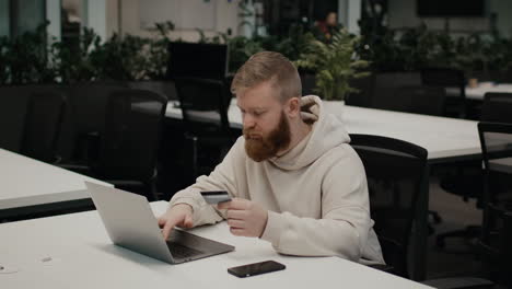 man paying online with credit card in modern office