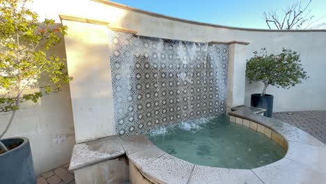 slow motion decorative ornate tiled water fountain cascading in bright sunny walled garden