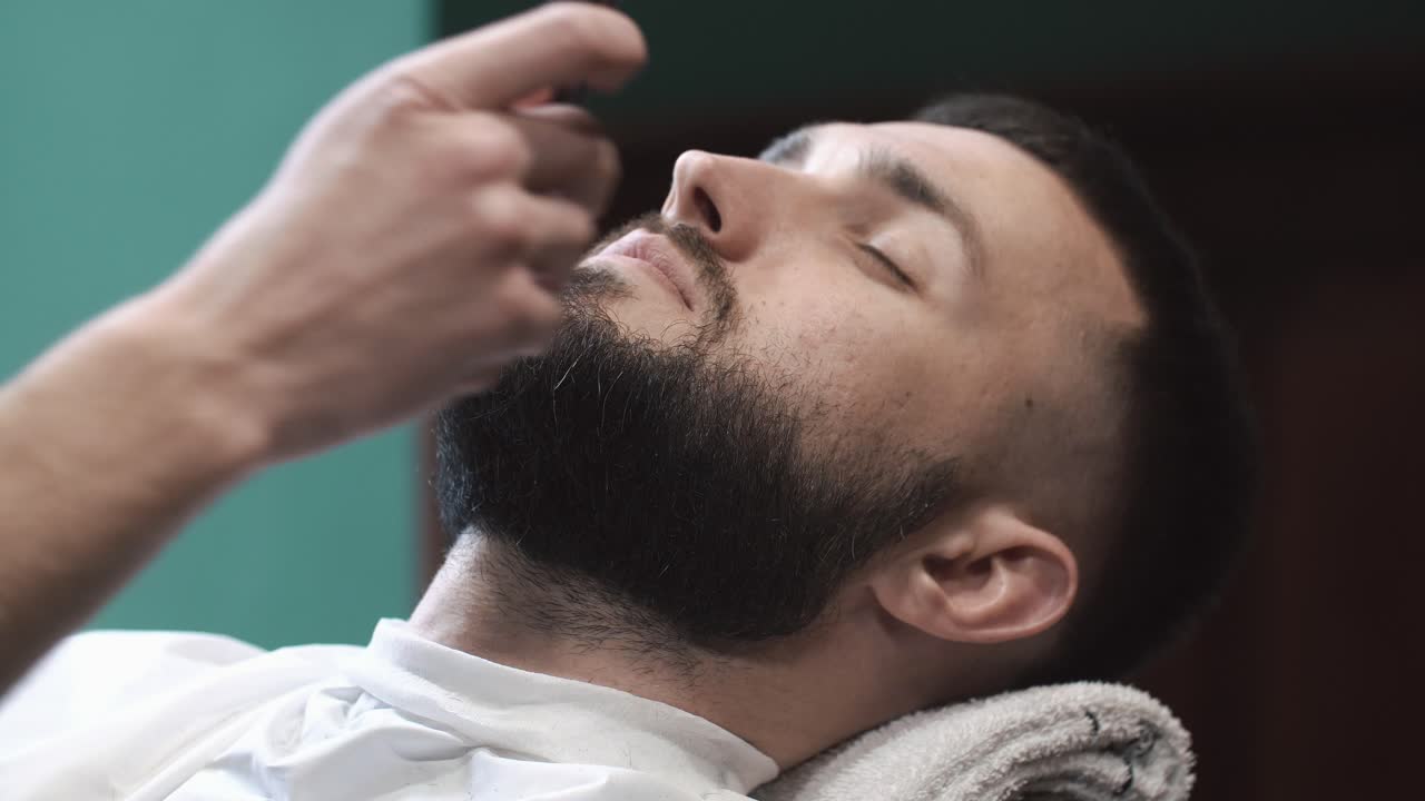 A man getting his beard groomed or trimmed at a barbershop