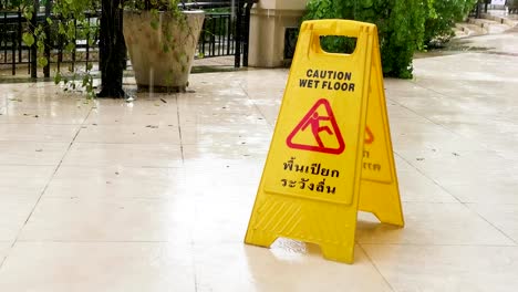 yellow caution sign with wet floor and in thai language in thailand