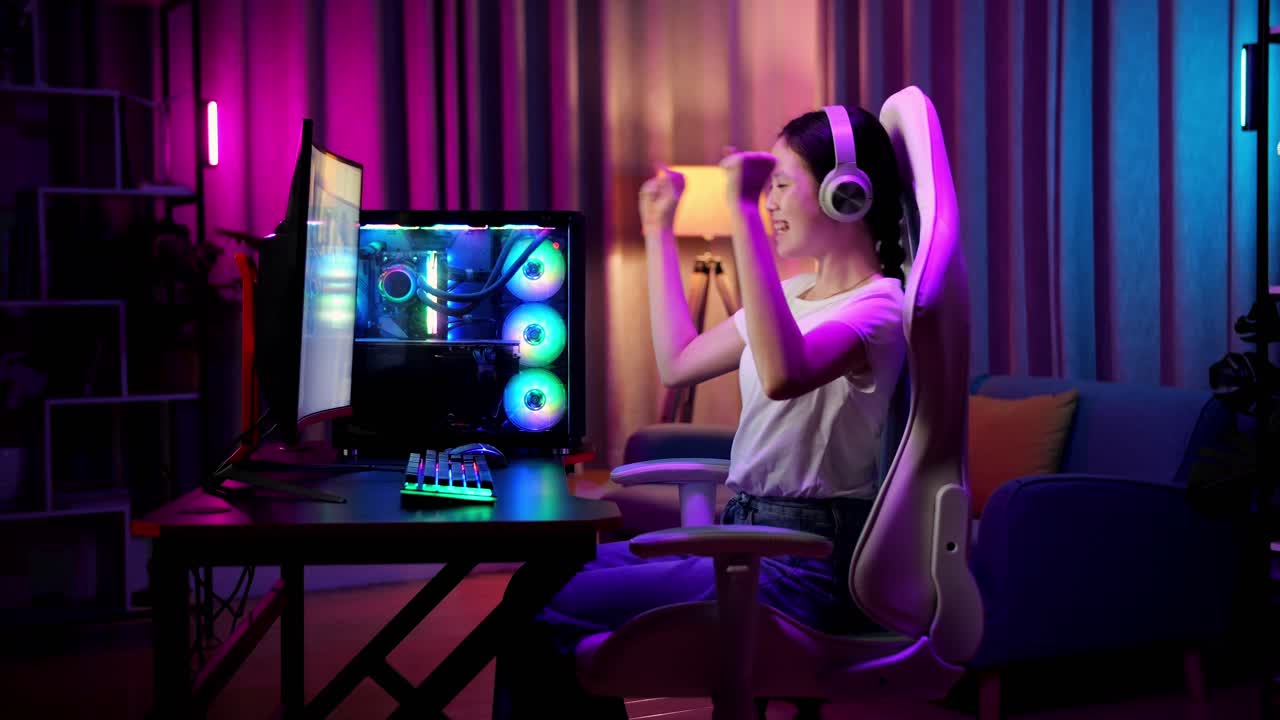 una adolescente asiática emocionada celebra la victoria y baila mientras juega videojuegos en la computadora