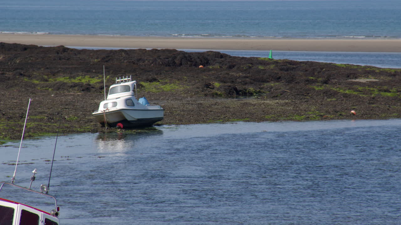Long shot of a small beached boat at low tide at Newport sands, parrog