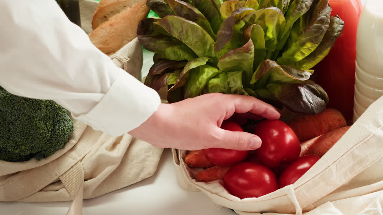 Person Picking Up a Tomato from a Grocery Bag